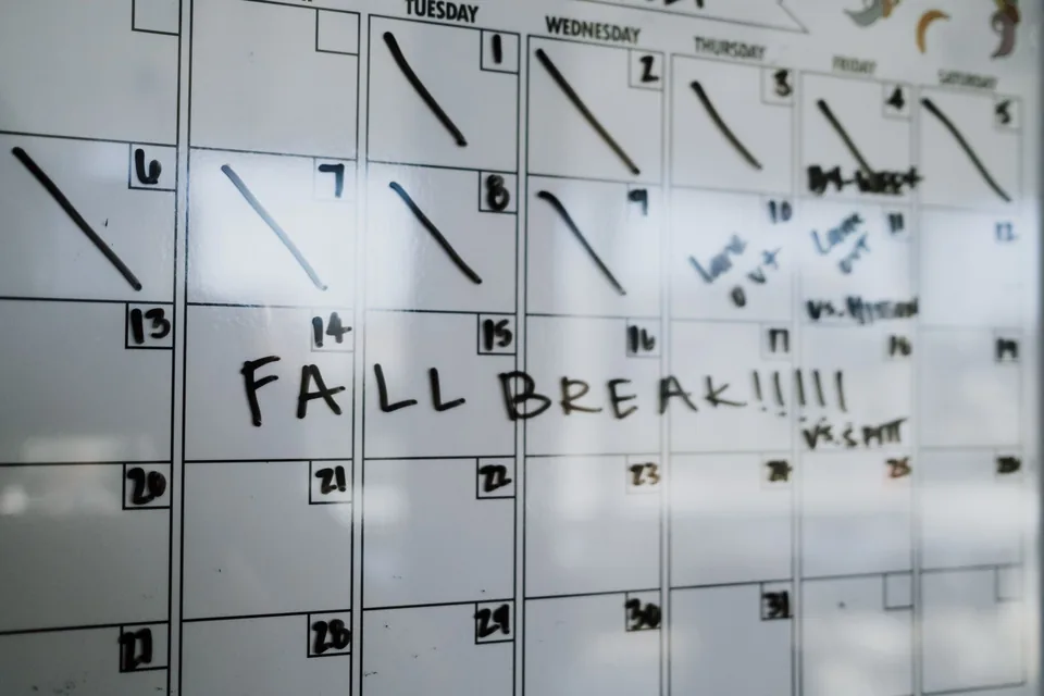 A whiteboard month calendar with the first weeks struck off day by day, scrawled notes on the days after, and FALL BREAK written across a week.